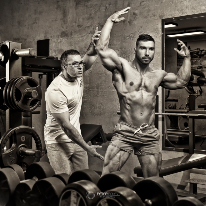 Bodybuilder guided by his trainer for correct posing.